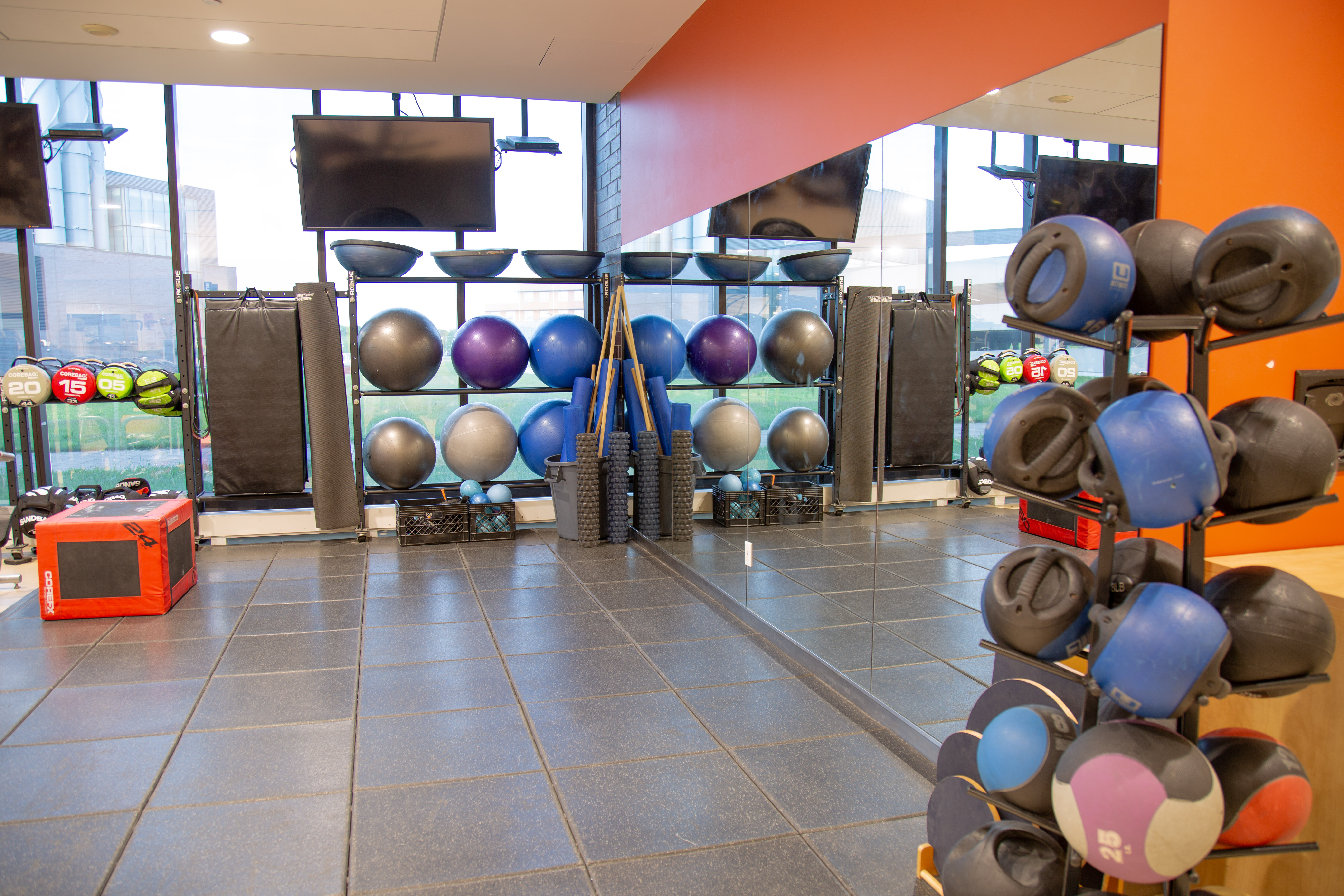 Modern gym corner with exercise balls, kettlebells, and a large mirror reflecting the workout area.
