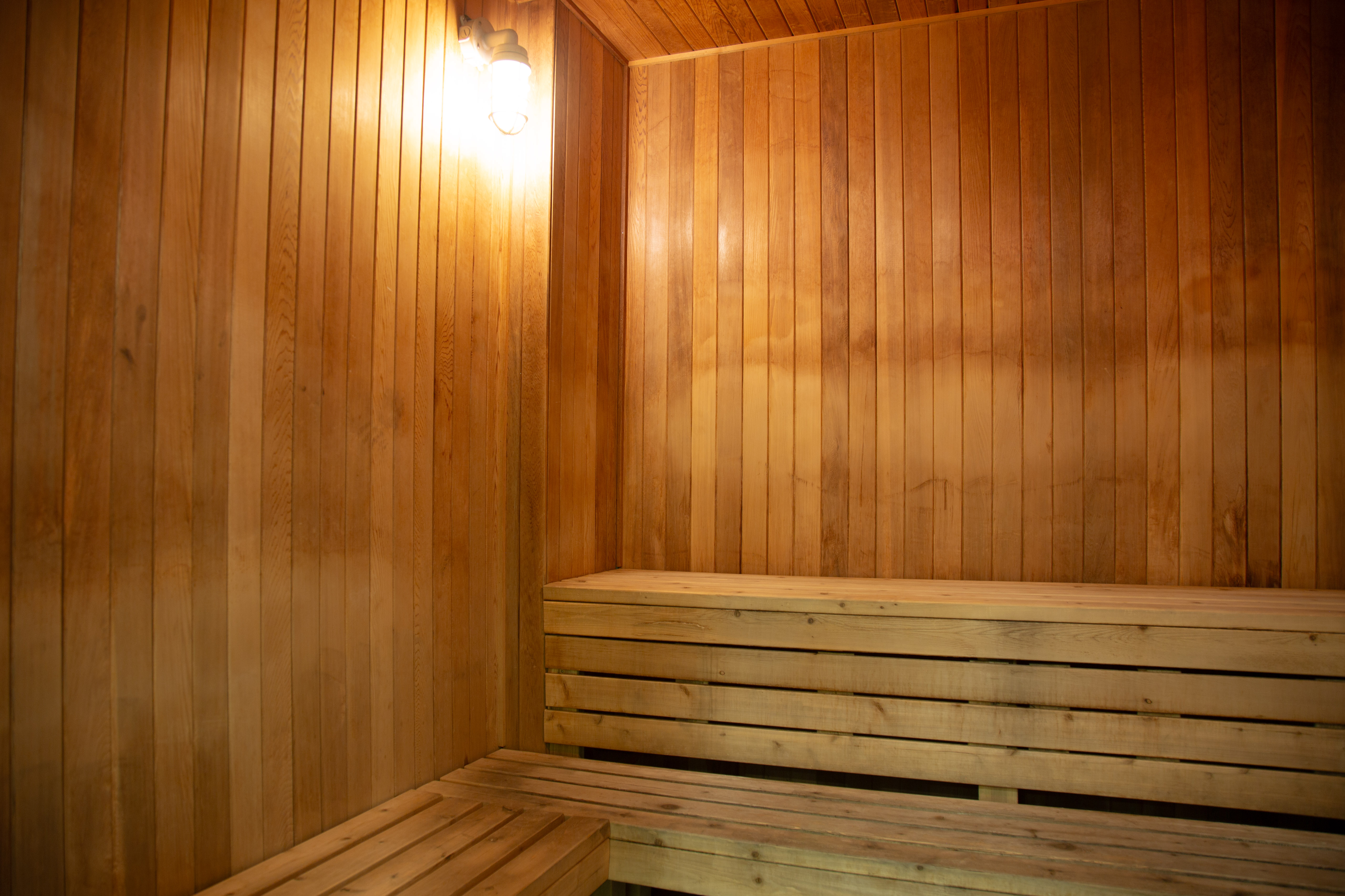 Interior of a wooden sauna room with warm lighting and tiered bench seating along the walls.
