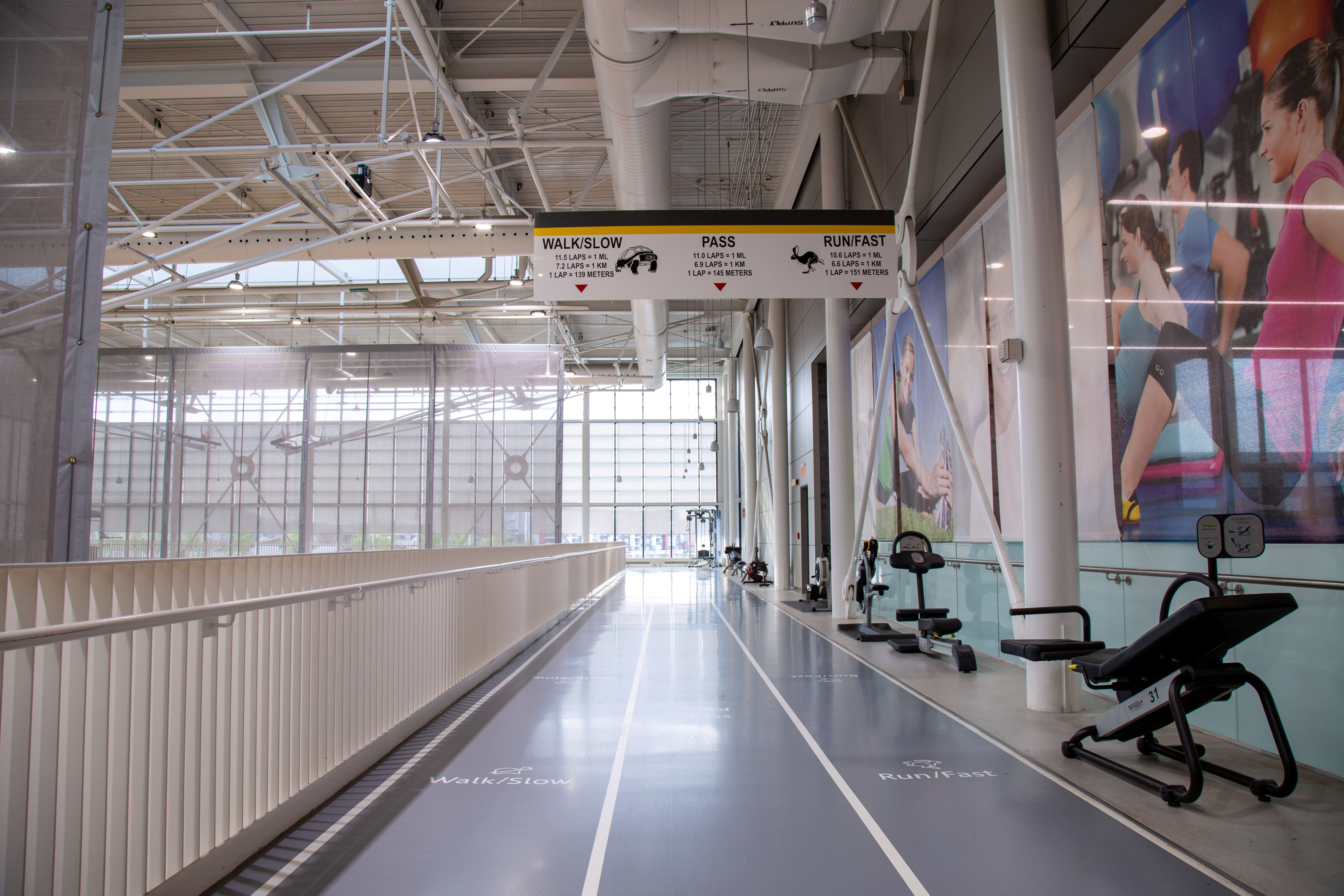 Indoor running track with lanes marked for walking, passing, and running fast inside a spacious gym facility.