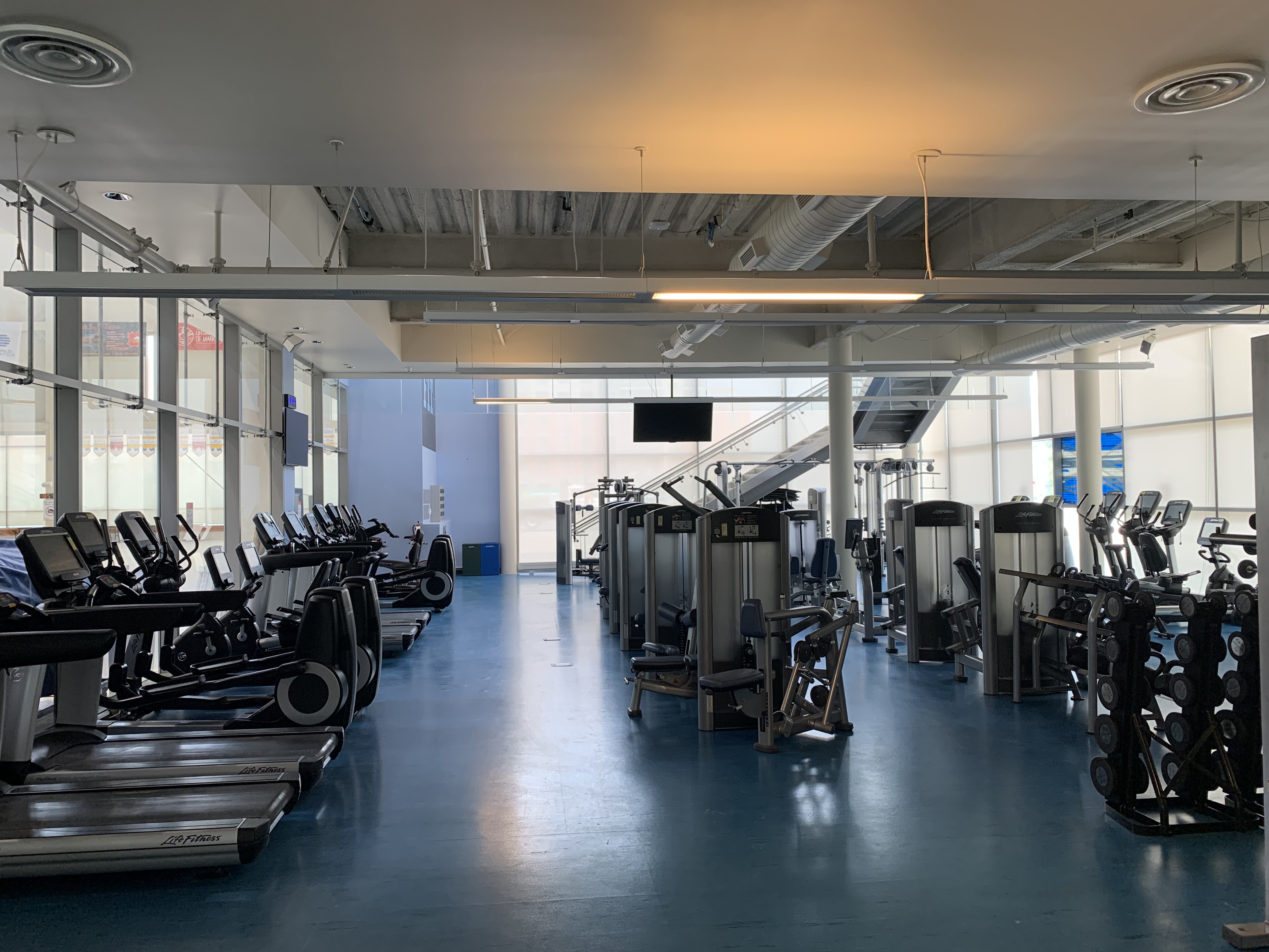 Wide shot of gym interior showing weighted machines, treadmills and free weights.