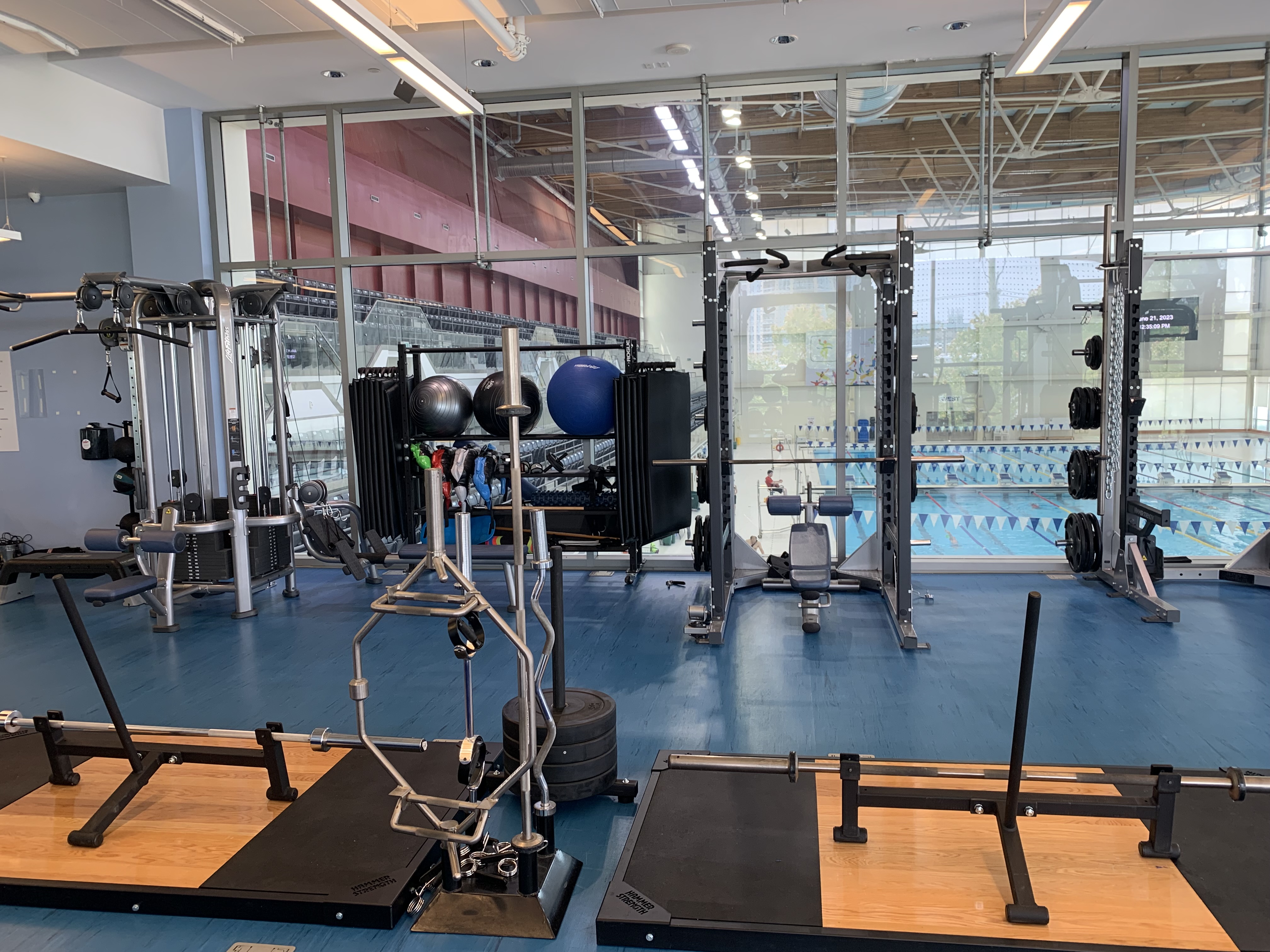 Gym interior with multiple squat racks and deadlift platforms.