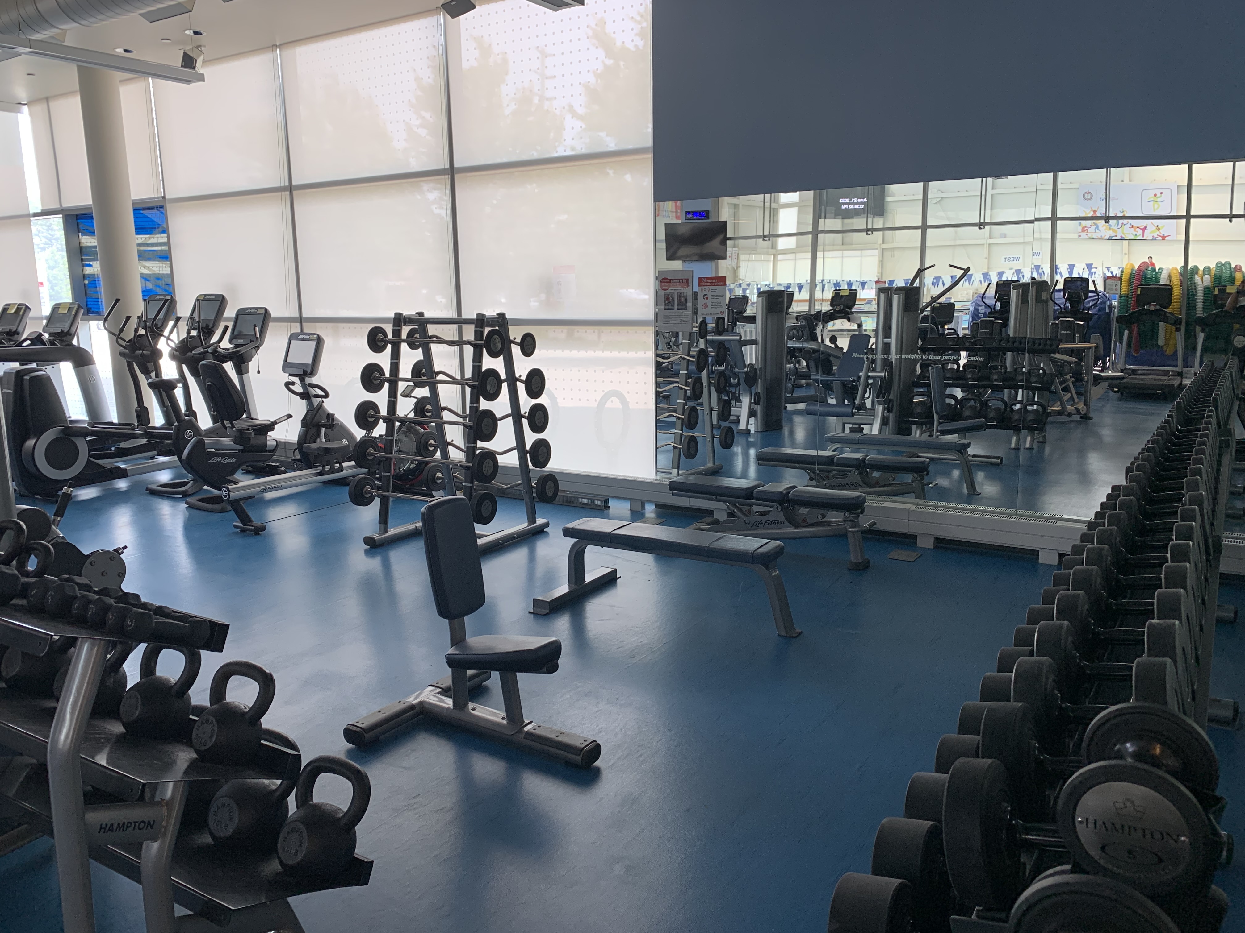 Free weight section of gym with benches and dumbbells.