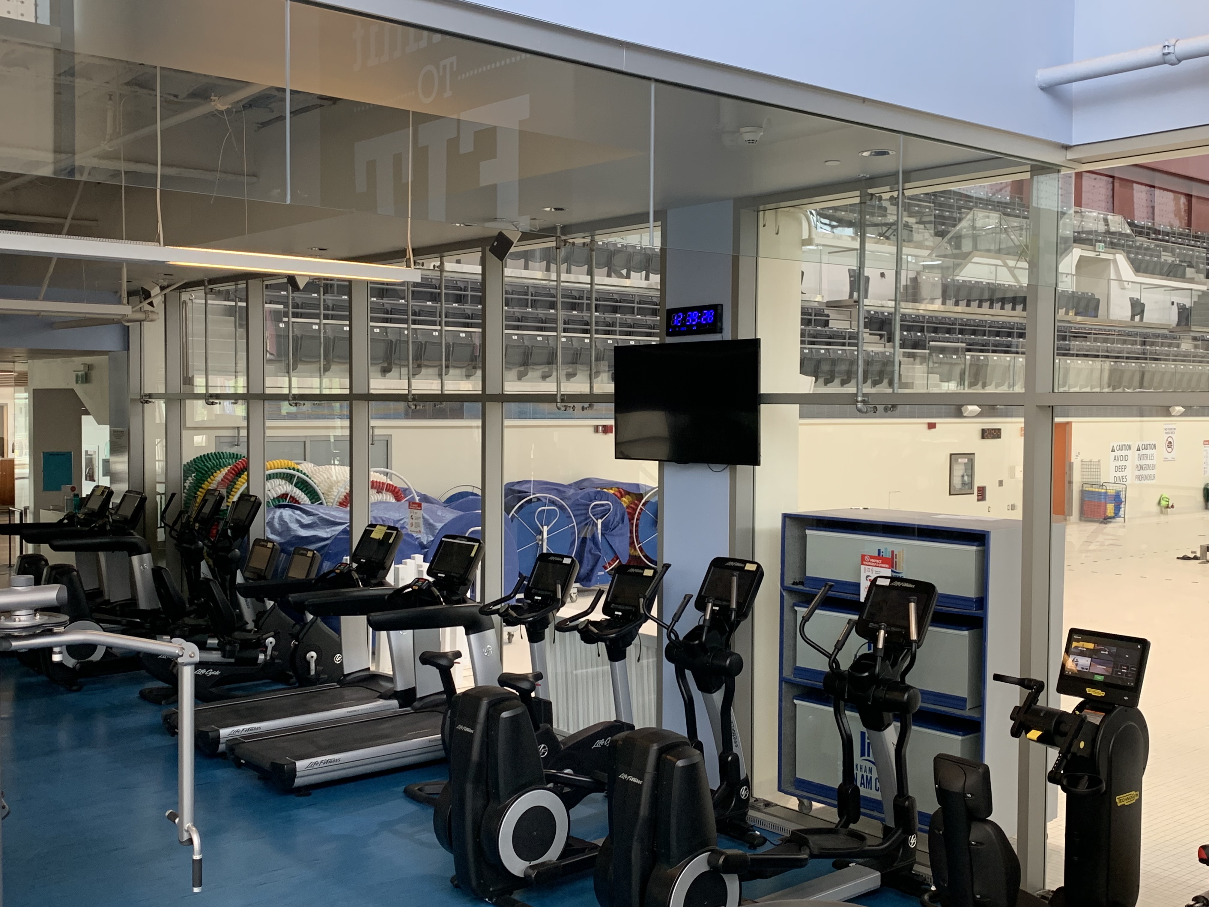 Cardio equipment in gym overlooking a pool.