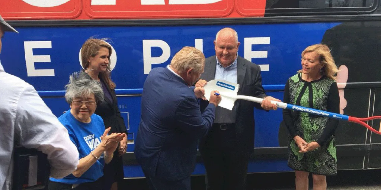 Frank Scrapitti holding a shovel while Doug Ford signs it.
