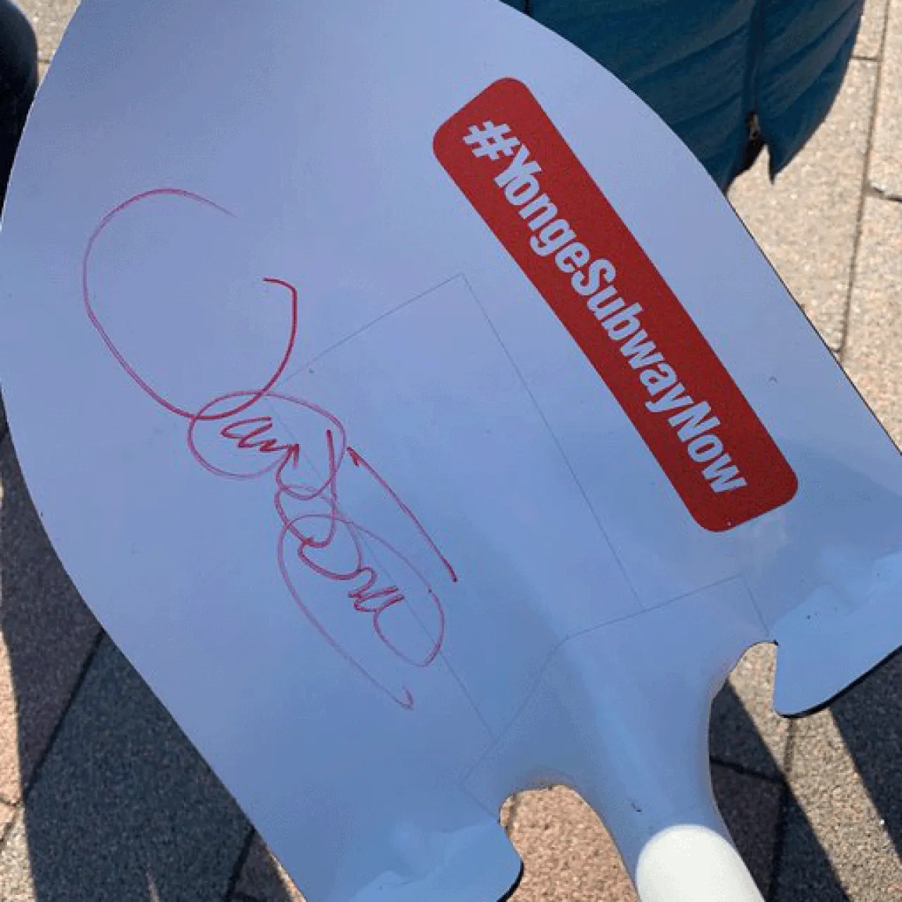 Shovel with a signature on it and a sticker that says Yonge Subway Now.