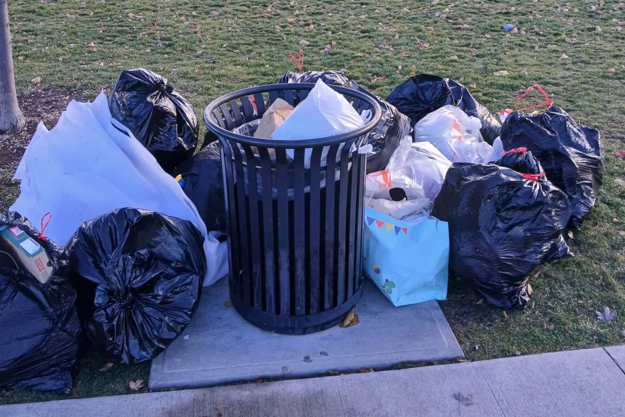 Garbage overflowing an outdoor waste bin.