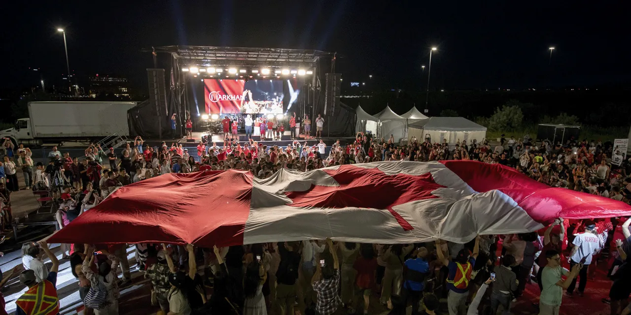 Canadian flag over crowd at event.