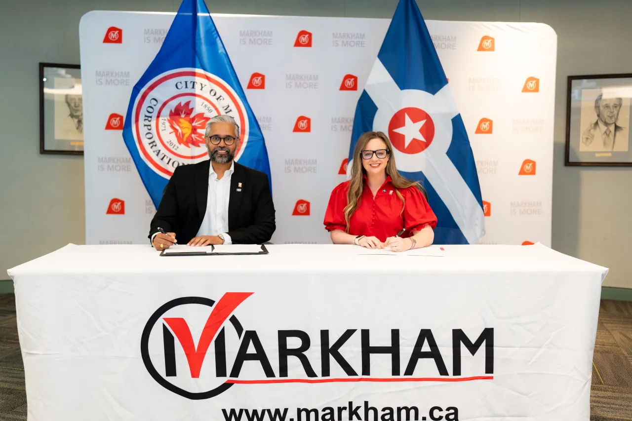 Officials from The Corporation of the City of Markham and Indy Economic Development Inc. sit at a table, each signing a document.