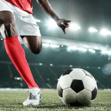 Soccer player in a stadium winding up to kick the ball.