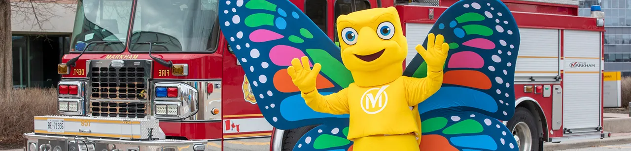 Millie butterfly mascot in front of a Markham fire truck.