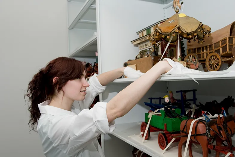 Person with white gloves handling antique items.