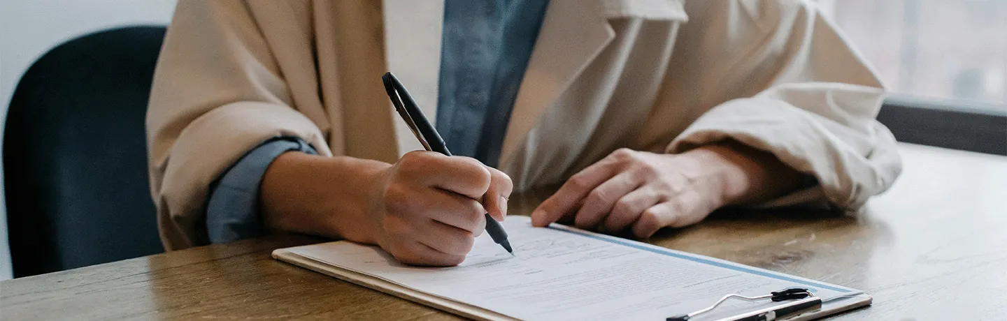 Person writing on clipboard