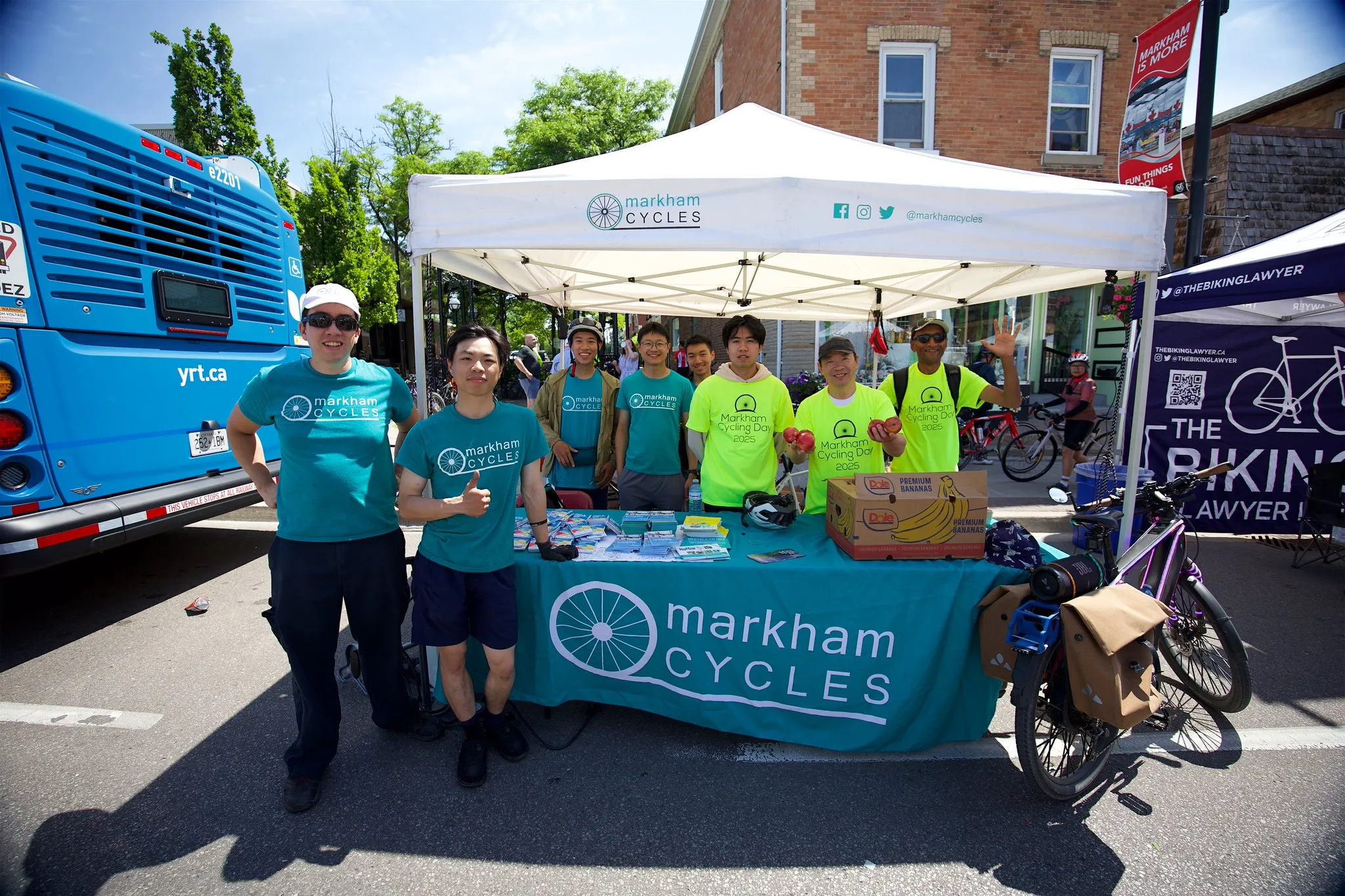 Cycling day volunteers and Markham Cycles staff at event under a tent.