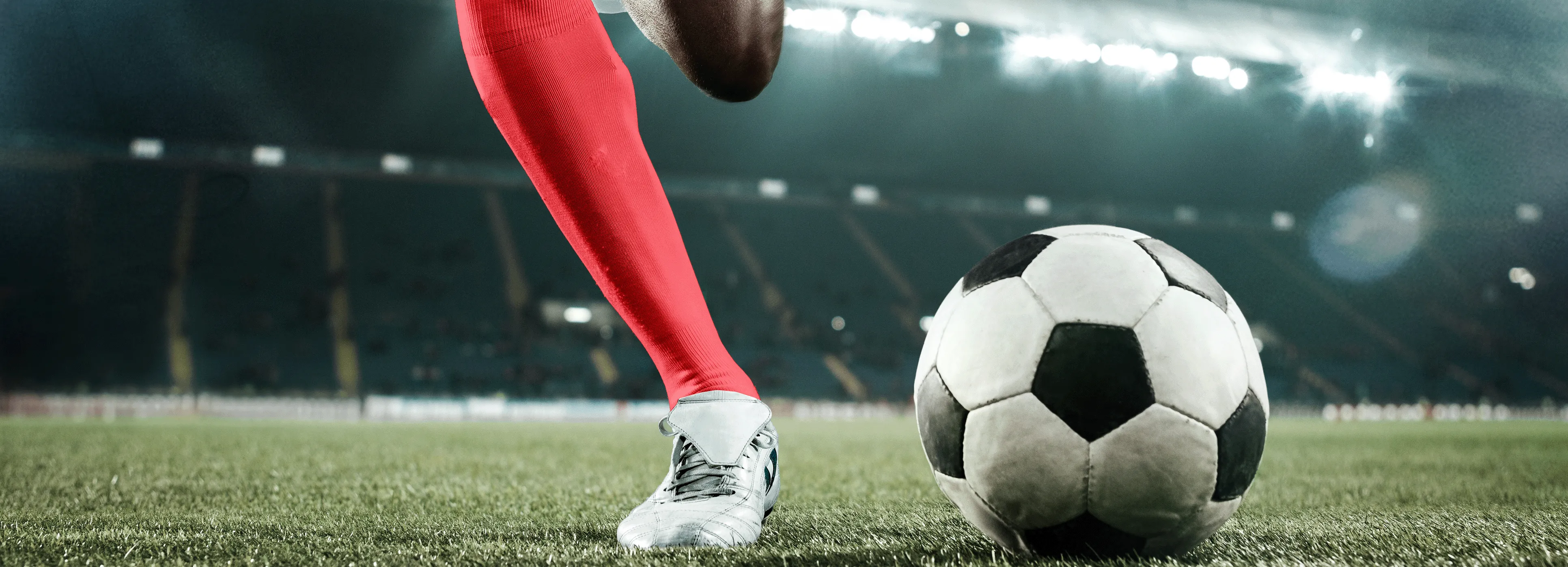 Soccer player in a stadium winding up to kick the ball.
