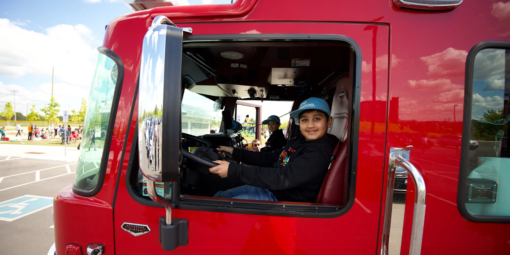 Child touring parked fire truck sitting in the front seat