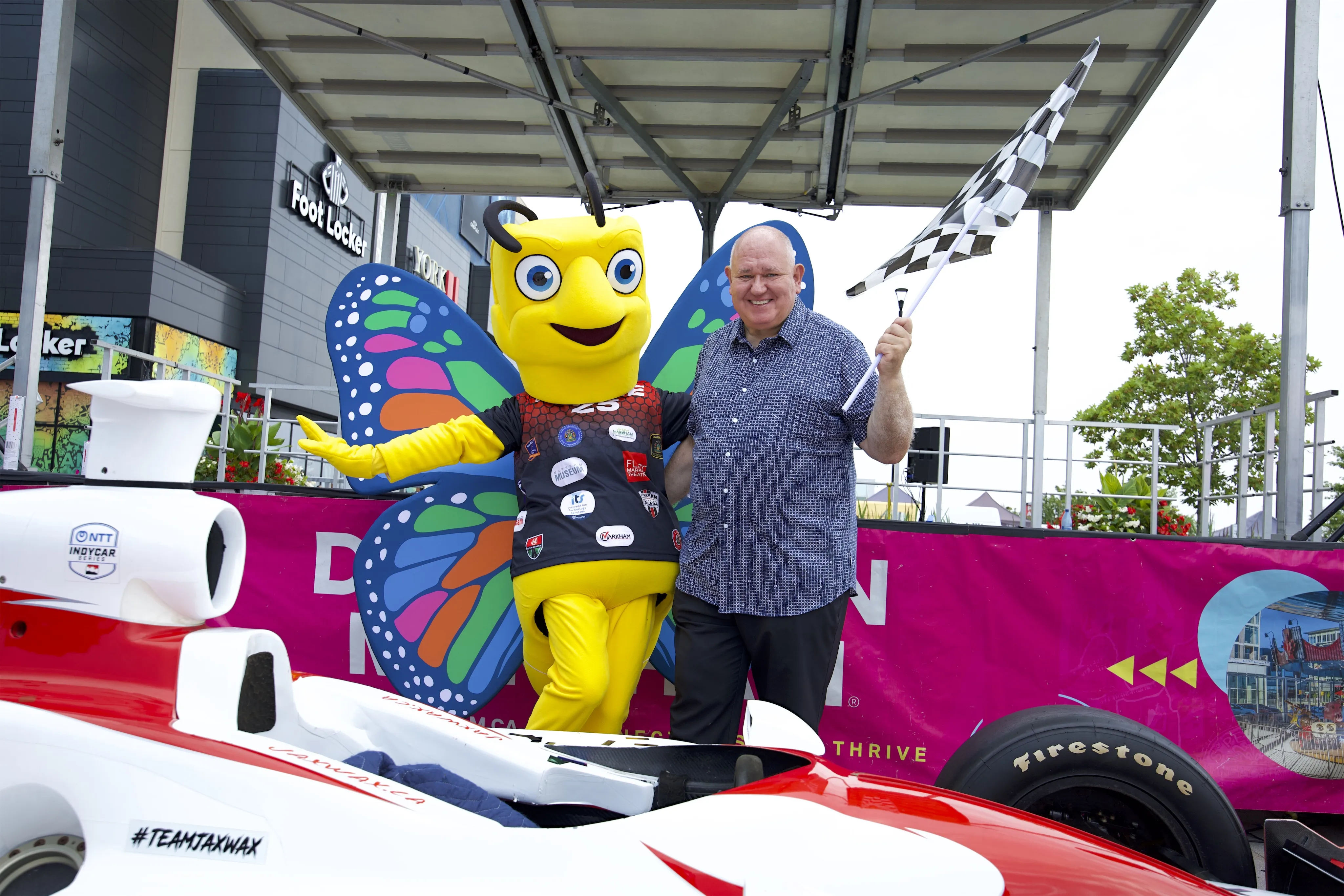 City of Markham's Mayor with Millie mascot holding race flags.