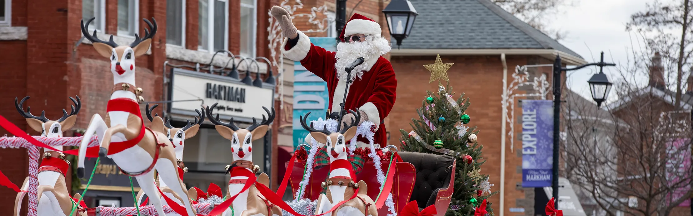 Santa Claus on parade float waving to crowd.